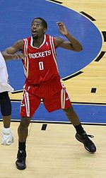 A basketball player, wearing a red jersey with the word «HOUSTON» and the number 0 on the front, stands on a basketball court.